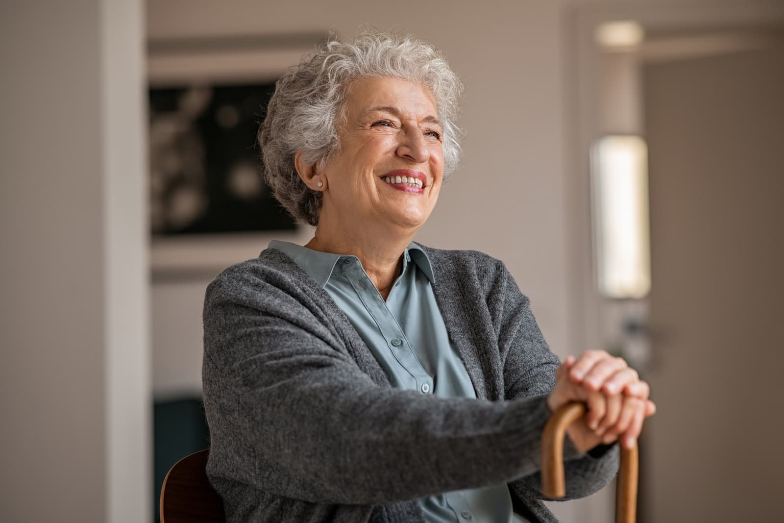 An older woman smiling while resting on her walking cane